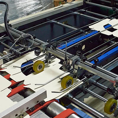 Вклейка пластиковых окошек в высеченные картонные заготовки автоматическим способом.